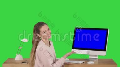一位迷人的女士在电脑屏幕上展示了一些东西，她正在和摄像机交谈，屏幕上是一个绿色的蓝屏模拟显示屏